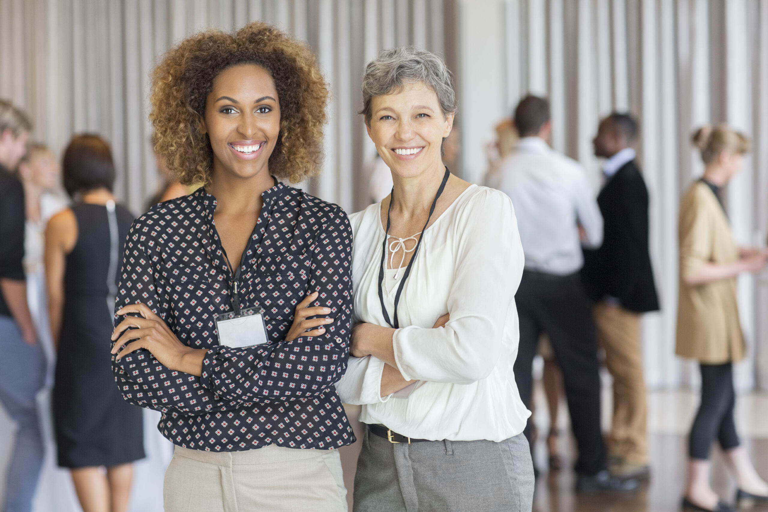 Two businesswomen posing in front of a group gathering